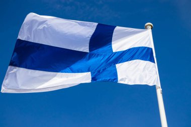 Mavi gökyüzüne karşı esen Finlandiya ulusal bayrağı