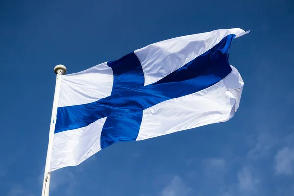 Mavi gökyüzüne karşı esen Finlandiya ulusal bayrağı