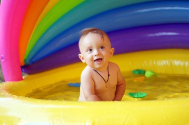 Şişme bebek havuzunda oynayan çocuk. Çocuk yüzme ve splash renkli Bahçe Merkezi oynamak. Sıcak yaz gününde su oyuncakları ile oynarken mutlu çocuk.         