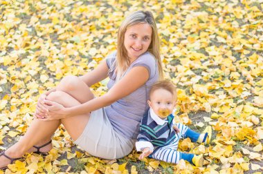 Mutlu anne ve küçük sarı ile oynarken oğlu gülümseyen parkta bırakır. Sonbahar.