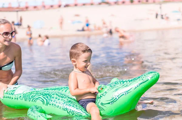 Маленький хлопчик грає з іграшковим крокодилом в озері — стокове фото