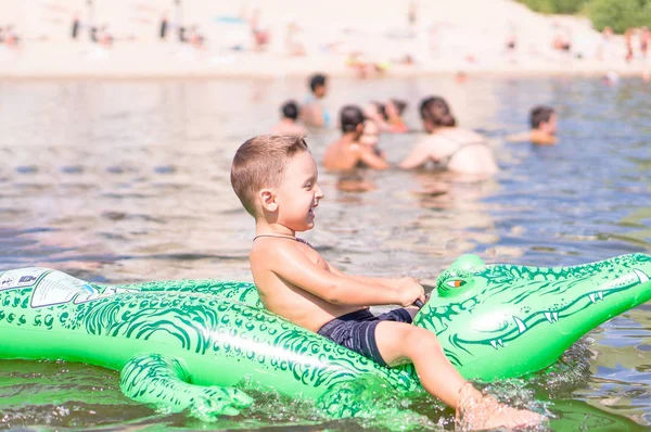 Усміхнений маленький хлопчик грає з іграшковим крокодилом в озері — стокове фото