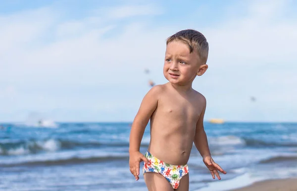 Netter kleiner Junge mit Blick auf das Meer am Strand — Stockfoto