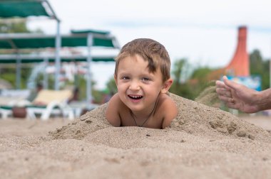 Kumda oynayan küçük boy gülümseyerek