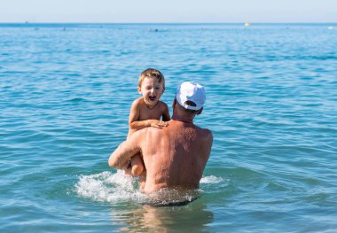 Mutlu bir aile. Gülümseyen Dede ve torunu denizde oynarken.