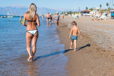 Genç anne ve çocuk evlat kumsalda gün Uuna bebeğim