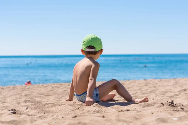 Junge sitzt und spielt mit dem Sand — Stockfoto