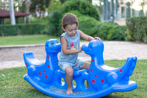 Усміхнений щасливий маленький хлопчик проводить час у парку, граючи з блакитними драконами — стокове фото