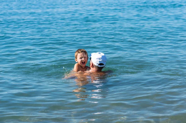 Ευτυχισμένη οικογένεια. Παππούς και εγγονός χαμογελαστός που παίζουν στη θάλασσα. Θετικά ανθρώπινα συναισθήματα, συναισθήματα, χαρά. — Φωτογραφία Αρχείου