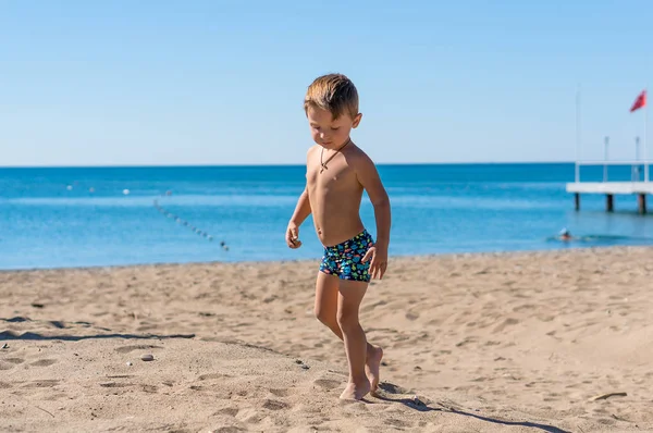 Lächelnder kleiner Junge, der sitzt und mit dem Sand spielt. positive menschliche Emotionen, Gefühle, Freude. — Stockfoto