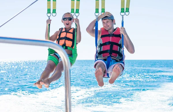 Gelukkige paar Parasailing in Dominicana strand in de zomer. Paar onder de parachute opknoping medio lucht. Plezier. Tropisch paradijs. Positieve menselijke emoties, gevoelens, vreugde. — Stockfoto