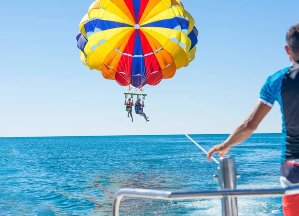 Счастливая пара парасейлинг на пляже Доминиканы летом. Пара под парашютом, висящая в воздухе. Веселюсь. Тропический рай. Положительные человеческие эмоции, чувства, радость . — стоковое фото