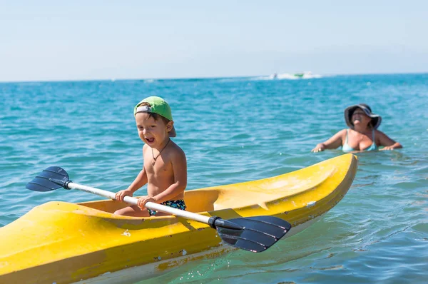 Abuela y nieto sonriendo niño pequeño en verde gorra de béisbol kayak — Foto de Stock