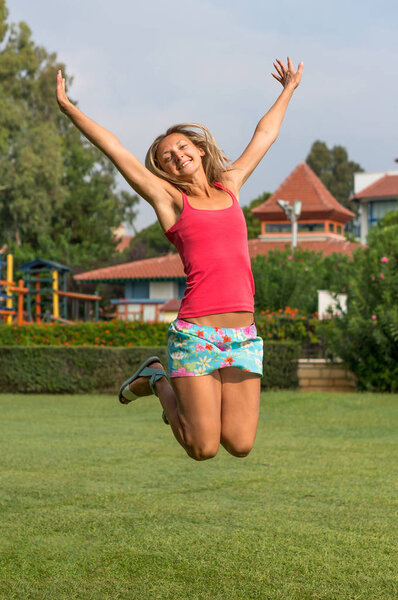 Attractive young smiling beautiful curly blonde hair slim girl fashion portrait in pink T-shirt posing looking away calm look,