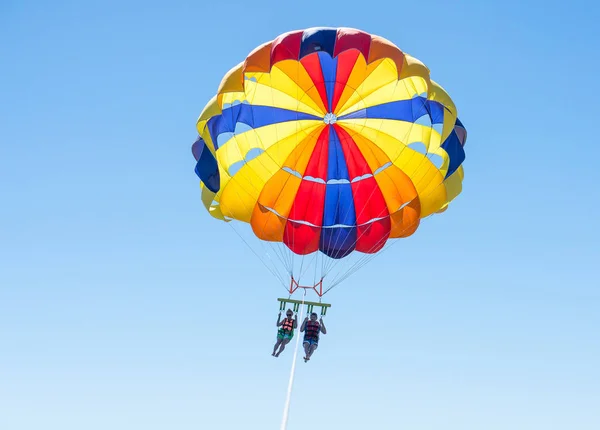 Happy couple Parasailing in Dominicana beach in summer. Couple under parachute hanging mid air. Having fun. Tropical Paradise. Positive human emotions, feelings, joy. — Stock Photo, Image