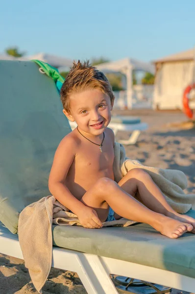 Lächelnder kleiner Junge, der im Sand in der Nähe des Meeres, des Ozeans spielt. positive menschliche Emotionen — Stockfoto