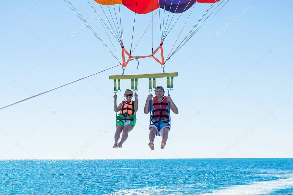 Happy couple Parasailing in Dominicana beach in summer. 