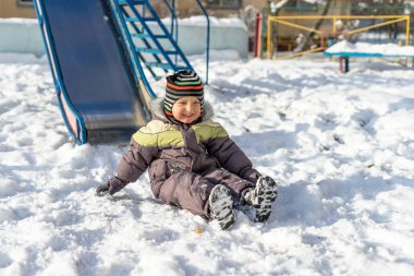 Eğleniyor karlı parkta yürümeye başlayan çocuk gülümseyen. Etkin kış oyunu. Mutlu bir aile.