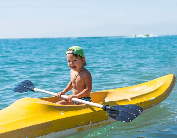 Petit garçon souriant dans la casquette de baseball verte kayak à la mer de l'océan tropical dans la journée. Émotions humaines positives, sentiments, joie. drôle mignon enfant faire des vacances et profiter de l'été . — Photo