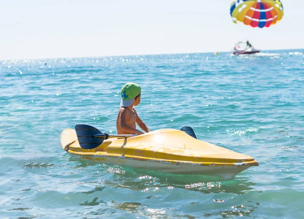 Niño sonriente con gorra de béisbol verde haciendo kayak en el mar tropical del océano durante el día. Emociones humanas positivas, sentimientos, alegría. Divertido lindo niño haciendo vacaciones y disfrutando summe — Foto de Stock