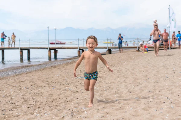 Усміхнений маленький хлопчик грає в морі на заході сонця. Позитивні людські емоції, почуття, радість. Портрет щасливого маленького хлопчика на березі океану. Весела мила дитина робить відпустку, насолоджуючись літом . — стокове фото