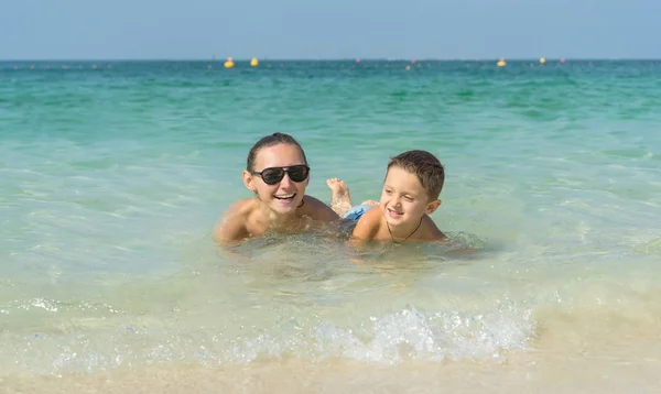 Happy smiling family having fun on tropical white beach (Maldives islands). Mother and cute son. Positive human emotions, feelings, joy. Spring, summer and winter holidays.