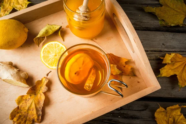 Una taza de té caliente con limón y jengibre en una mesa rústica — Foto de Stock