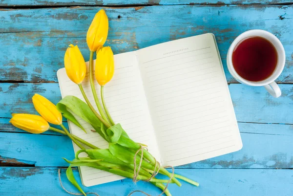 Té, tulipanes y cuaderno sobre mesa azul —  Fotos de Stock