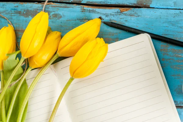 Tulipanes y cuaderno sobre mesa azul —  Fotos de Stock