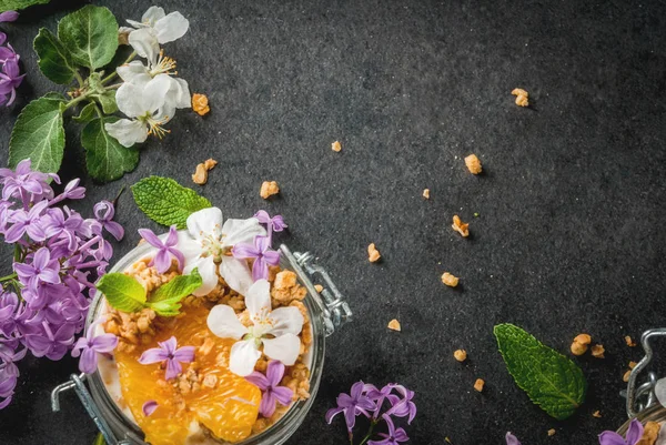 Yoghurt med granola, apelsin, mynta och ätbara blommor — Stockfoto