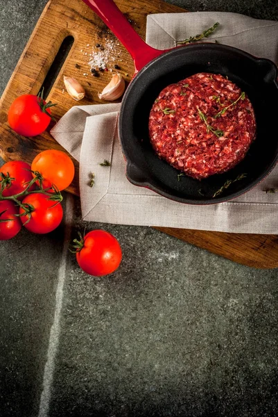 Carne de vaca orgânica crua hambúrgueres costeletas com especiarias, tomilho, tomate — Fotografia de Stock