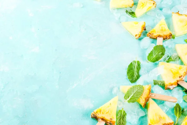 Trancher les bâtonnets d'ananas et les feuilles de menthe, sur du bleu clair b — Photo