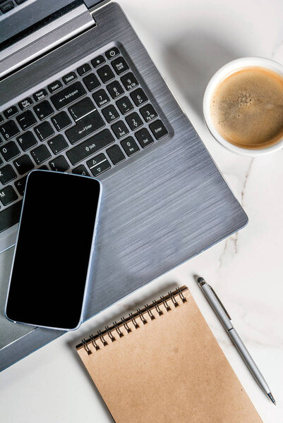 Workplace, white desk table with laptop, smartphone, coffee cup 