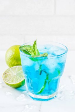 Renkli yaz yiyecek, içecek, buzlu mavi lagün alkol kokteyl içki limon ve nane, beyaz mermer zemin kopya alanı ile
