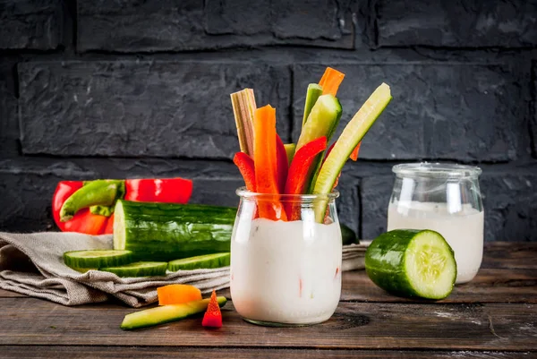 夏季健康小吃开胃菜 各种五颜六色的新鲜蔬菜棒 黄瓜和胡萝卜 与酸奶酱蘸 木材和深色混凝土背景复制空间 — 图库照片