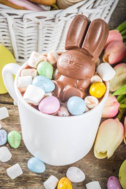 Çikolatalı tavşanlı sıcak Paskalya çikolatası. Paskalya yumurtaları ve marşmelov, bahar çiçekleriyle ahşap zemin kopyalama alanı