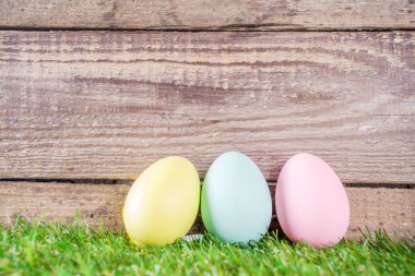 Renkli paskalya yumurtaları yeşil ve ahşap bahçe terasında. Komik bahar dekorasyonu. Mutlu Paskalya tebrik kartı geçmişi. 