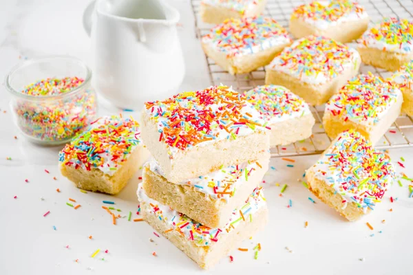 Frosted Sugar Cookie Bars, with sugar topping and colorful sugar crumbles, white marble background copy space