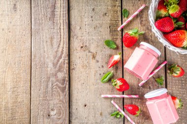 Çilekli milkshake şişede, taze çilek ve nane şekerli güneş ışığı yaz tahtası ve cam arka plan, kopyalama alanı