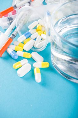 İlaç hapları konsepti, çeşitli haplar, tabletler ve kapsüller, tıbbi şırıngalar, termometre ve su bardakları, fotokopi alanı modeli, düz yatak.