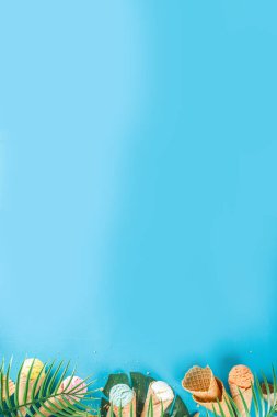 Dondurmalı waffle külahında çeşitli parlak renkli dondurma seti. Çikolatalı, yabanmersinli, şam fıstıklı, trend turkuaz arka planda ve tropikal palmiye yapraklı.