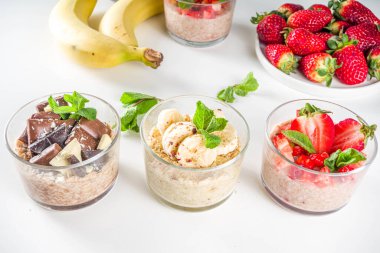 Bir gecede yulaf ezmesi hazırla. Çilekli yulaf lapası, muz, çikolata, küçük porsiyon kavanozlarda fındık. Yaz kahvaltısı yulafı. Sağlıklı vejetaryen diyeti.