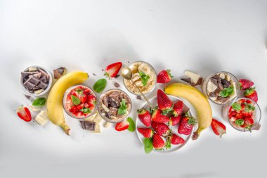 Bir gecede yulaf ezmesi hazırla. Çilekli yulaf lapası, muz, çikolata, küçük porsiyon kavanozlarda fındık. Yaz kahvaltısı yulafı. Sağlıklı vejetaryen diyeti.