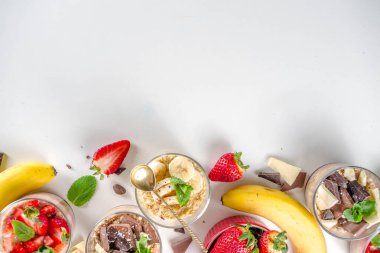 Bir gecede yulaf ezmesi hazırla. Çilekli yulaf lapası, muz, çikolata, küçük porsiyon kavanozlarda fındık. Yaz kahvaltısı yulafı. Sağlıklı vejetaryen diyeti.