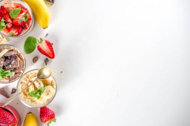 Bir gecede yulaf ezmesi hazırla. Çilekli yulaf lapası, muz, çikolata, küçük porsiyon kavanozlarda fındık. Yaz kahvaltısı yulafı. Sağlıklı vejetaryen diyeti.