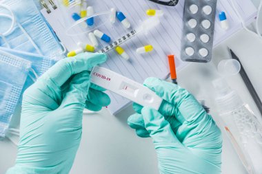 Dünya çapında koronavirüs salgını konsepti. Salgın COVID 19, 2019-NCoV. Antikor veya sars-cov-2 virüsü için laboratuvar test şeridi. Doktorun ellerinde. Haplar, aşı şırıngaları, defterler....