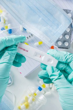 Dünya çapında koronavirüs salgını konsepti. Salgın COVID 19, 2019-NCoV. Antikor veya sars-cov-2 virüsü için laboratuvar test şeridi. Doktorun ellerinde. Haplar, aşı şırıngaları, defterler....