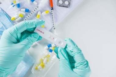 Dünya çapında koronavirüs salgını konsepti. Salgın COVID 19, 2019-NCoV. Antikor veya sars-cov-2 virüsü için laboratuvar test şeridi. Doktorun ellerinde. Haplar, aşı şırıngaları, defterler....