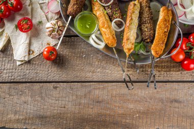 Yaz bbq partisi. Çubukta şiş kebap, kıyma ve tavuk etinden. Lula kebap, geleneksel Kafkas Asya yemeği. Çeşitli soslar, baharatlar ve domateslerle, gri taş arka plan, yukarıdaki boşluğu kopyala