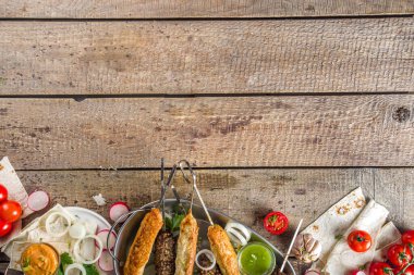 Yaz bbq partisi. Çubukta şiş kebap, kıyma ve tavuk etinden. Lula kebap, geleneksel Kafkas Asya yemeği. Çeşitli soslar, baharatlar ve domateslerle, gri taş arka plan, yukarıdaki boşluğu kopyala